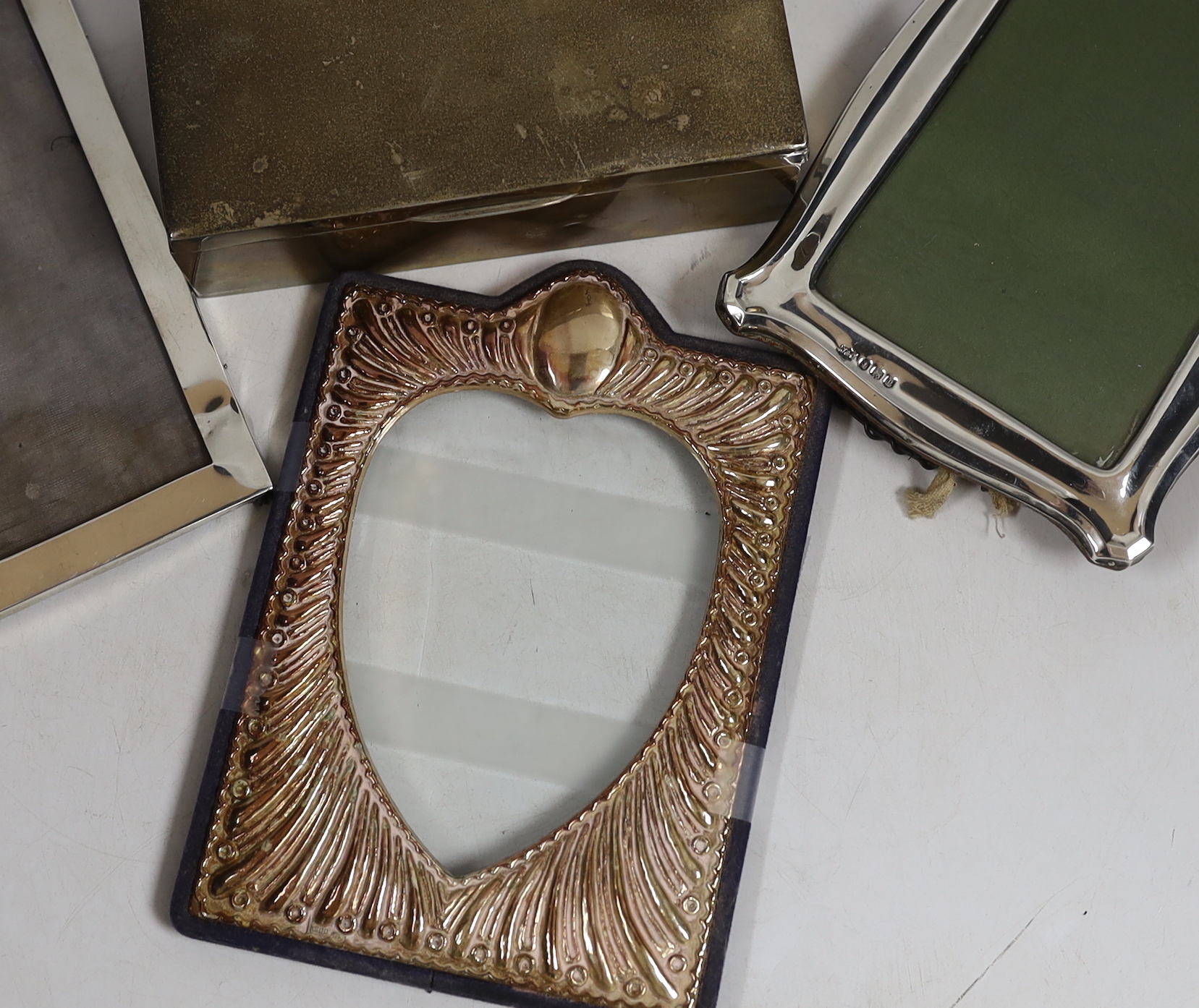 Two early to mid 20th century silver mounted photograph frames, largest 18cm, together with a George V silver mounted cigarette box.